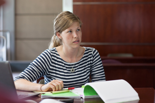 Student sitting with documents on the table while listening.