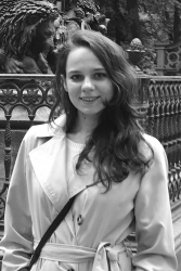 Dilyara Agisheva in a black and white photo, standing in front of an ornate statue