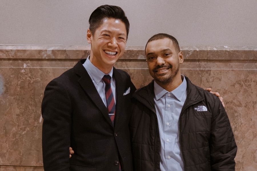 Two men stand together in a photo while smiling.