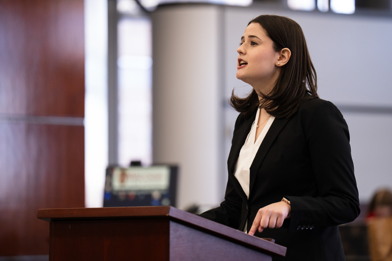 A photo of a young woman in business attire speaking.