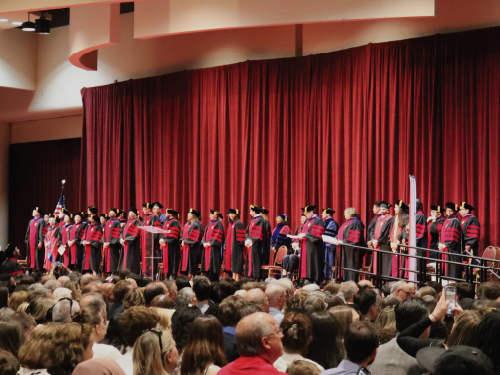 Graduating students and faculty gathered at the stage at the 2025 Hooding Ceremony