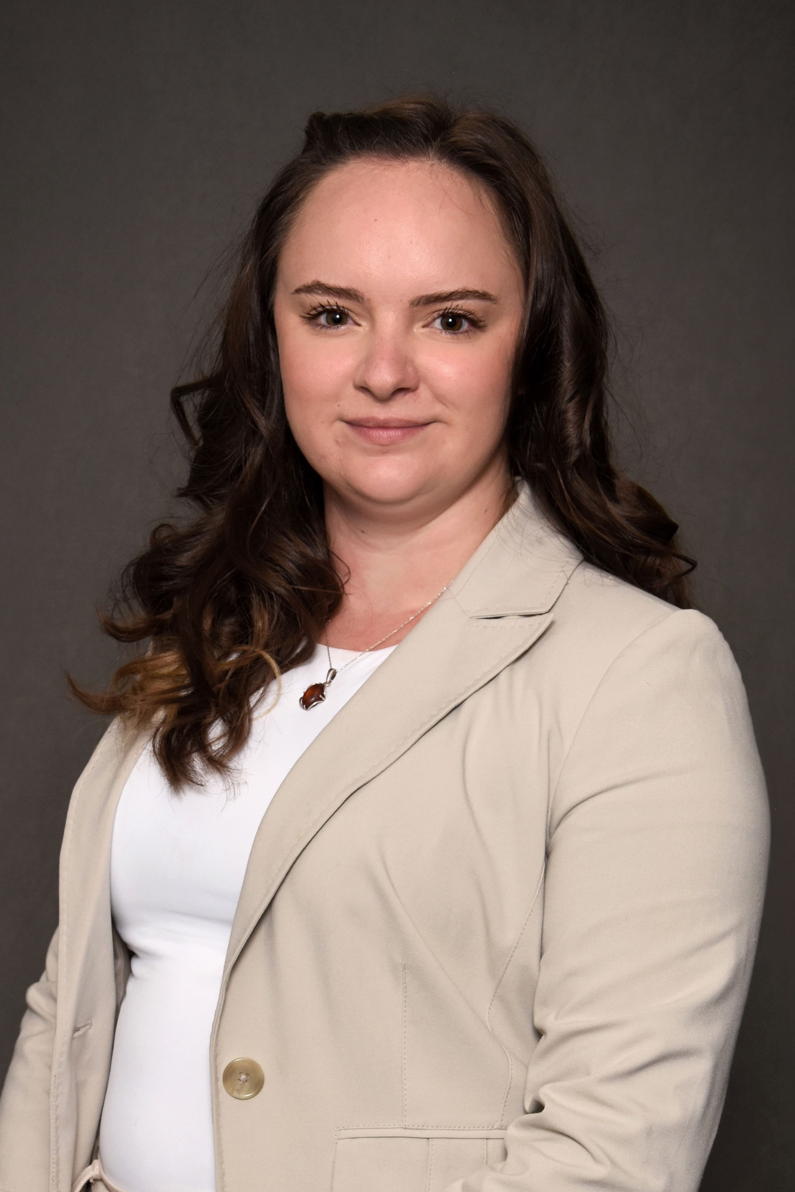 Student with dark brown hair in tan blazer and white shirt