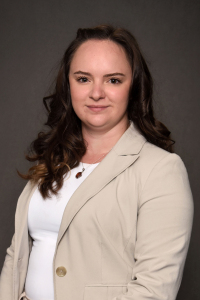 Student with dark brown hair in tan blazer and white shirt