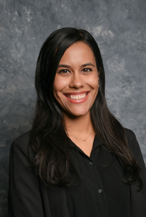 A headshot photo of Gabrielle Marquez smiling at the camera while wearing a black top with buttons.