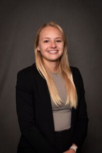 Woman with blonde hair, taupe shirt and black blazer